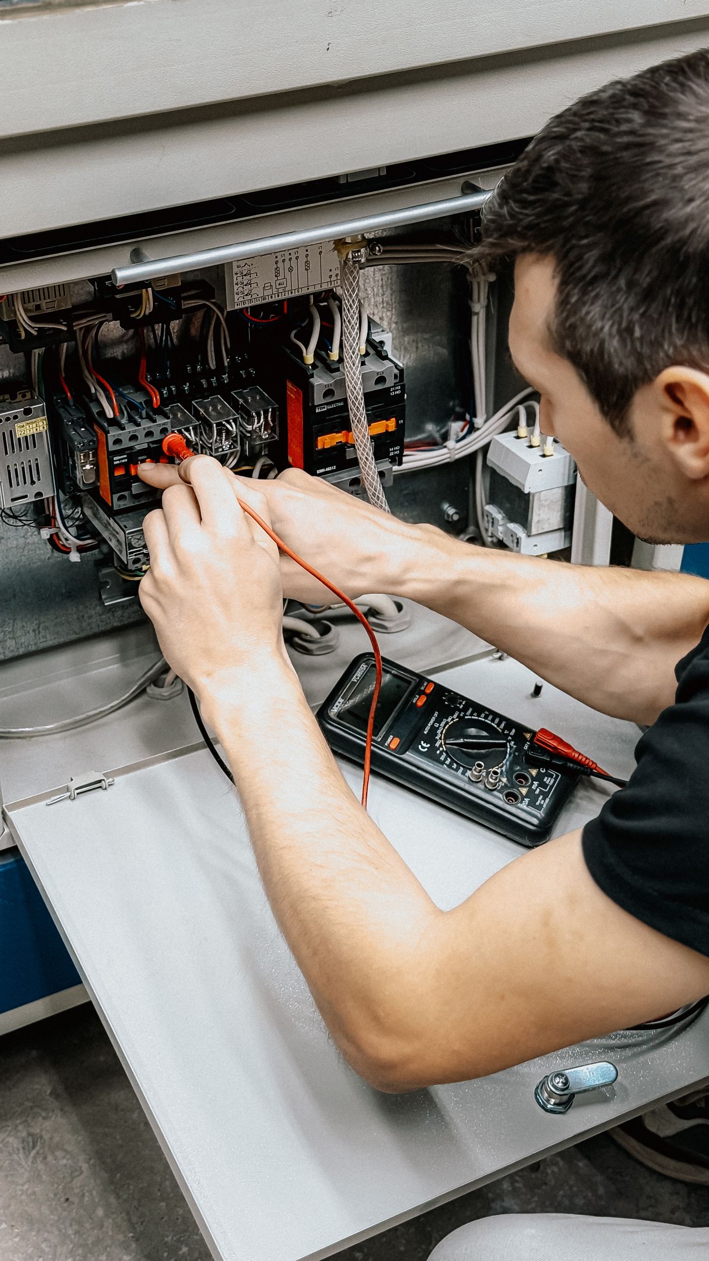 Electrician măsurând cu multimetrul într-un tablou electric